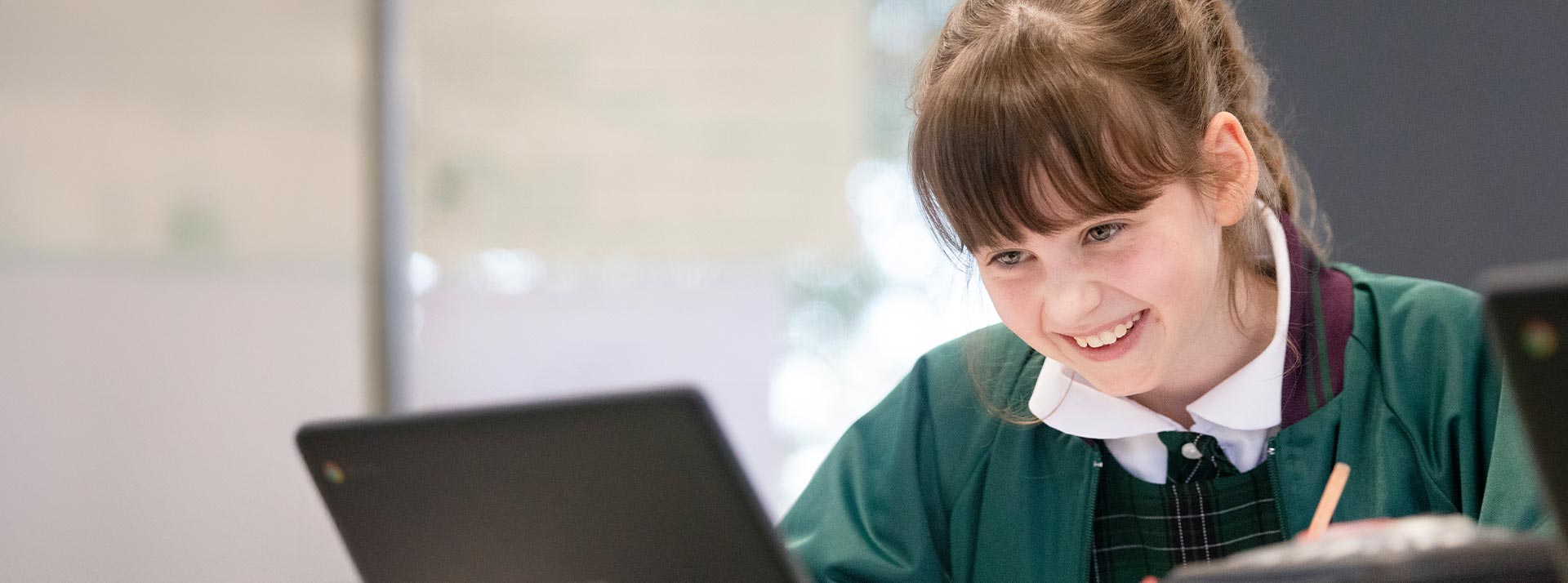 Holy Cross Glenwood student in class. The student is typing on her Chromebook.