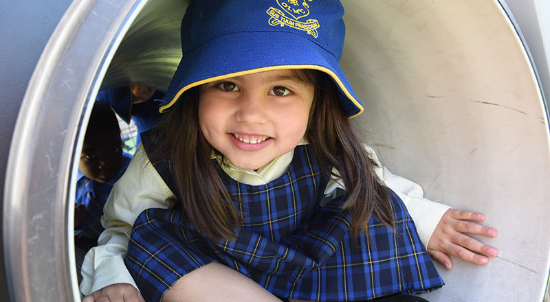 Happy OLMC Wentworthville student playing with School Playground slide