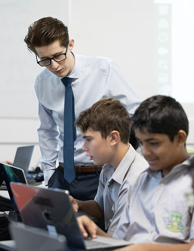 Parramatta Marist Westmead Male Teacher assisting students on laptops