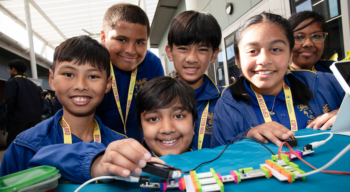 Happy CSPD students, showing off their STEM creation. The device has wires and a battery connected to it.